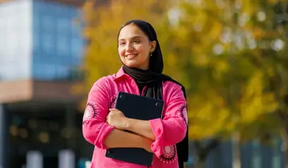Student smiling holding a folder