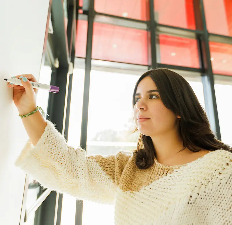 A student writes on a whiteboard