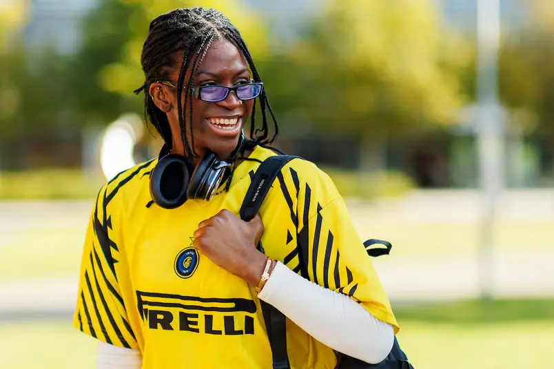 A student in a bright yellow jersey smiles and looks off camera