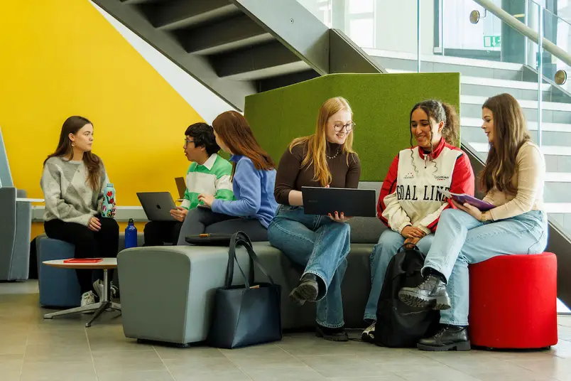 Students sit on colourful furniture in the foyer of Eolas