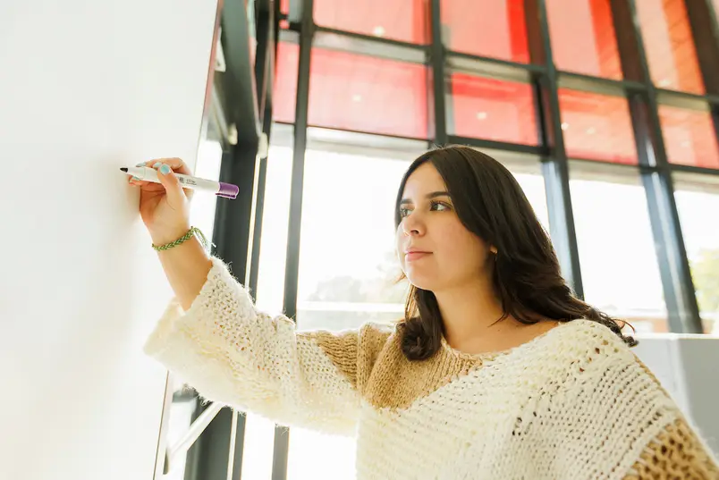 A student writes on a whiteboard