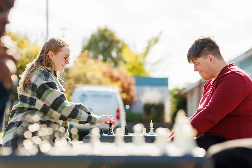 Two students play a game of chess on our outdoor chessboards