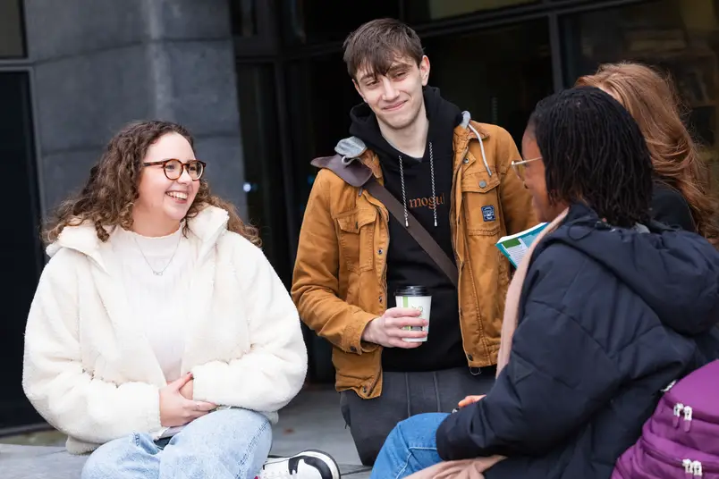 students sit on a purple bench and talk