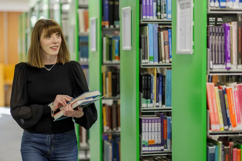 Amazed student walking alongside shelves in MU Library